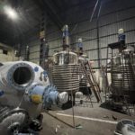 Assembly area at Raviraj Engineering with multiple stainless steel reactor vessels and process equipment.